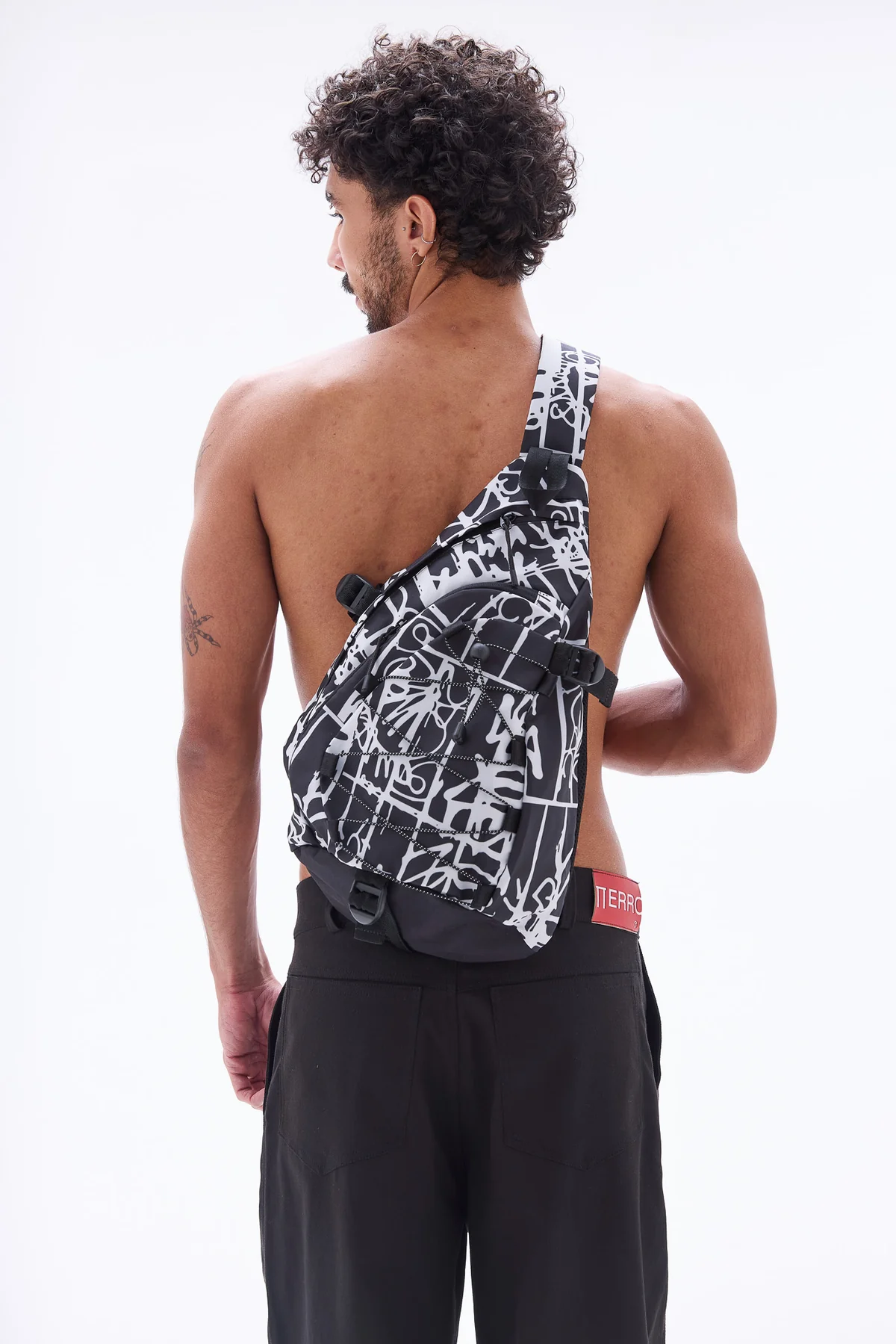 Sling Bag streetwear com estampa grafite e fivelas táticas